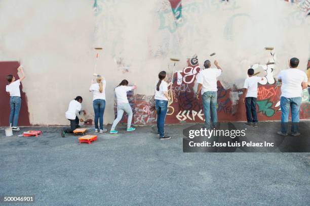 volunteers painting over graffiti wall - community helper stock pictures, royalty-free photos & images