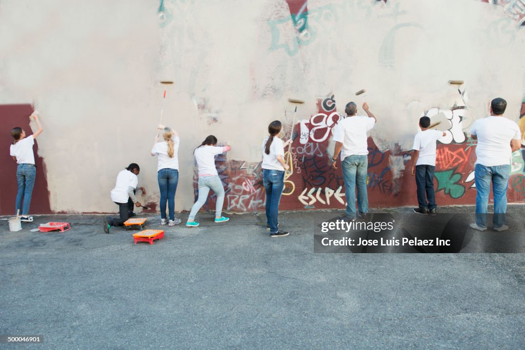 Volunteers painting over graffiti wall