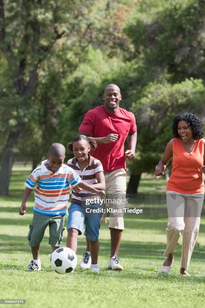 Family playing soccer in park