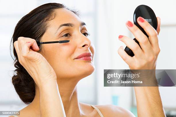 mixed race woman applying makeup - mature woman beauty stock pictures, royalty-free photos & images