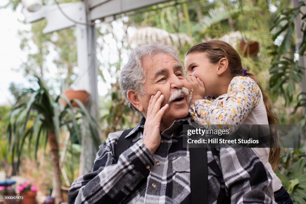 Senior Caucasian man and granddaughter whispering outdoors
