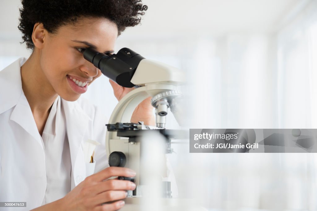 Black scientist using microscope in lab