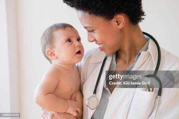 smiling doctor holding baby - doctor and baby stockfoto's en -beelden