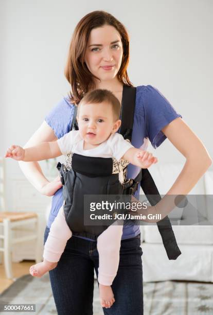 mother carrying baby in sling - baby carrier stock pictures, royalty-free photos & images