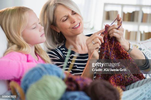 senior caucasian woman and granddaughter knitting on sofa - old granny knitting stock-fotos und bilder