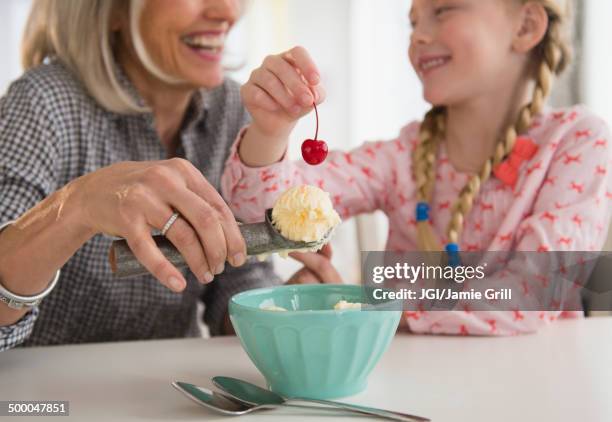 senior caucasian woman and granddaughter making ice cream sundae - ice cream sundae fotografías e imágenes de stock