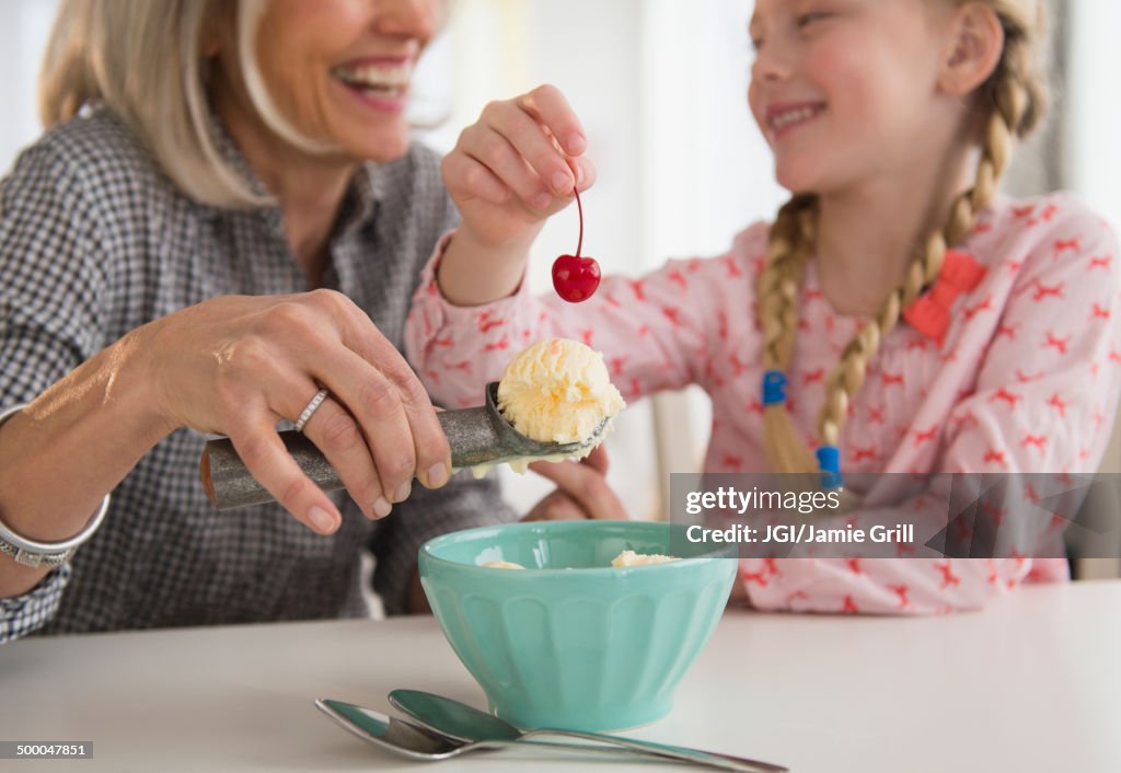 Senior Caucasian woman and granddaughter making ice cream sundae