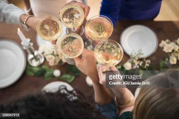 women toasting each other with champagne - friends toasting above table stock-fotos und bilder