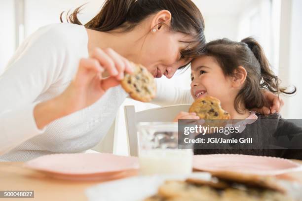 hispanic mother and daughter eating together - child loves chocolates stock-fotos und bilder