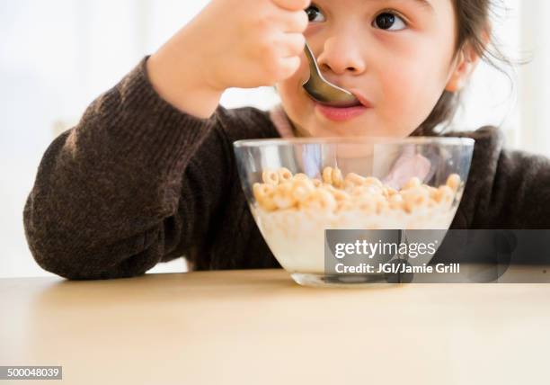 hispanic girl eating bowl of cereal - eating cereal stock pictures, royalty-free photos & images