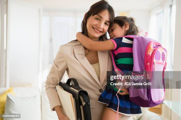 hispanic daughter hugging mother as she leaves for work - madre capofamiglia foto e immagini stock