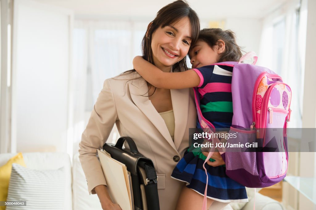 Hispanic daughter hugging mother as she leaves for work