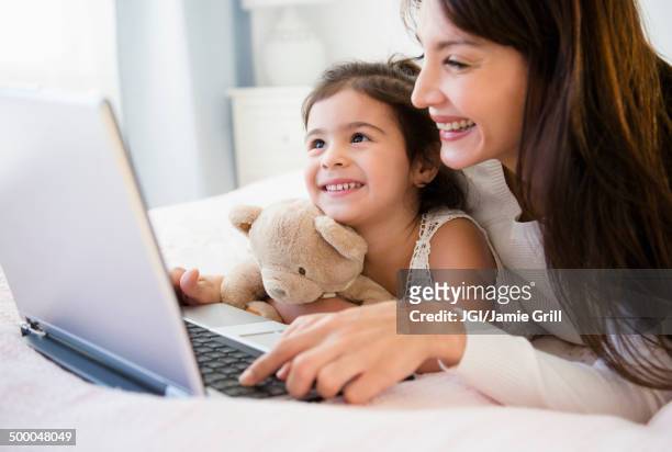 hispanic mother and daughter using laptop together - life of teddy stock pictures, royalty-free photos & images