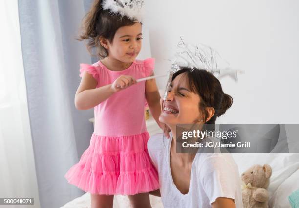 hispanic mother and daughter playing dress up on bed - objeto mágico imagens e fotografias de stock