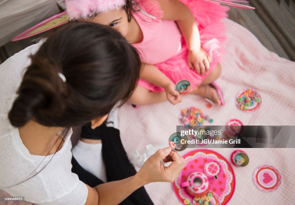 Hispanic mother and daughter having tea party