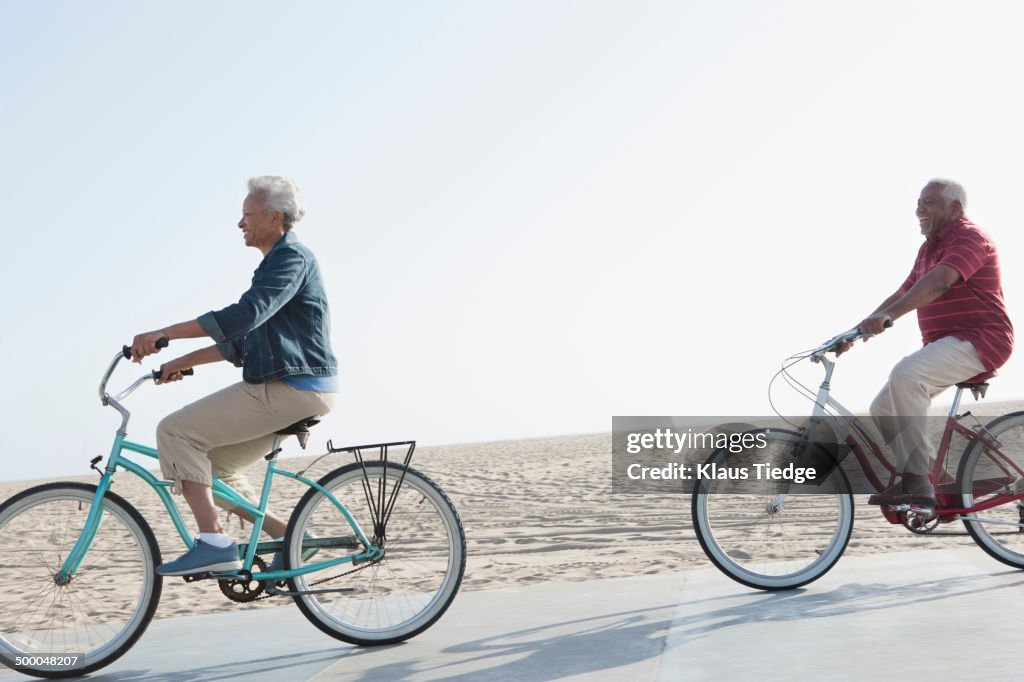 Senior African American couple riding bicycles by beach