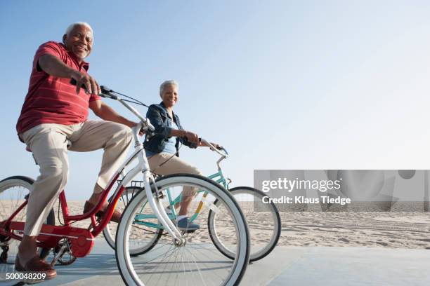 senior african american couple riding bicycles by beach - active seniors beach stock pictures, royalty-free photos & images