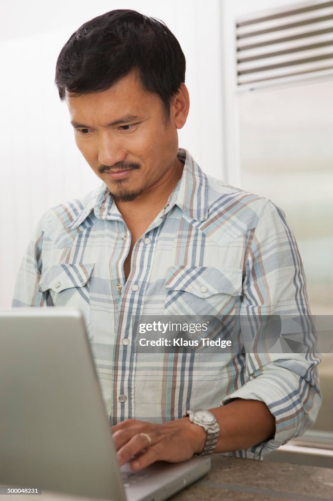 Asian man using laptop at desk