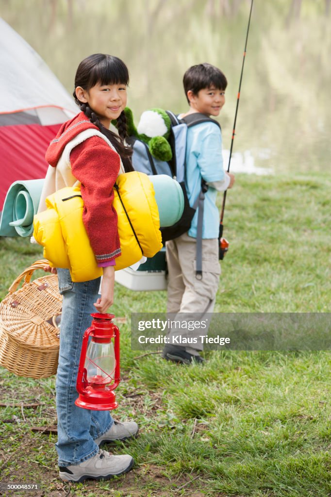 Children carrying camping gear outdoors
