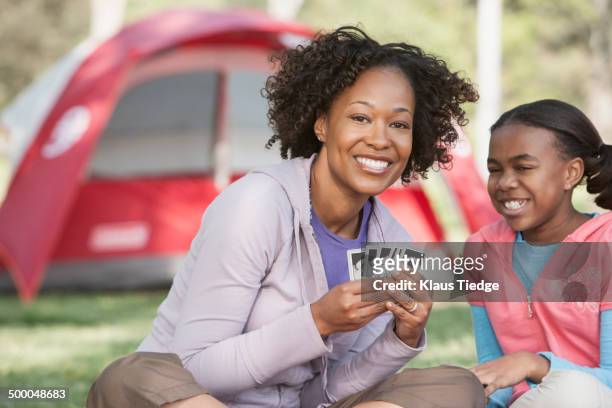 mother and daughter playing cards at campsite - camping games stockfoto's en -beelden