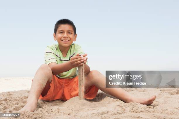 hispanic boy playing in sand on beach - black hair imagens e fotografias de stock
