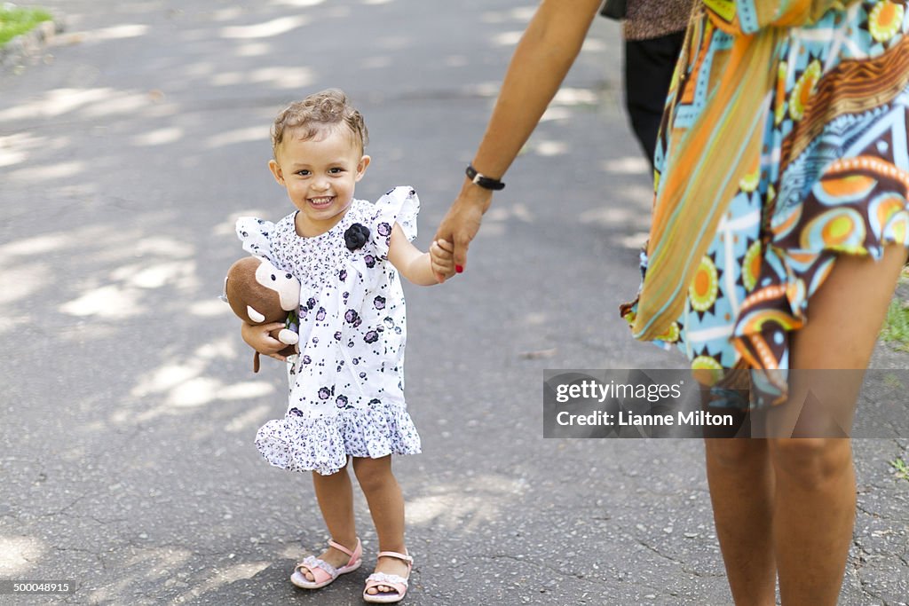 Mother and daughter walking on sidewalk