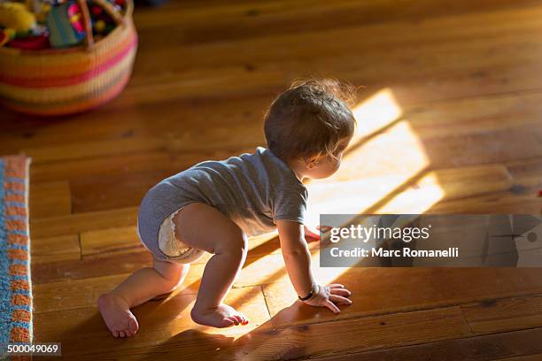 caucasian baby crawling on floor - baby light stock-fotos und bilder