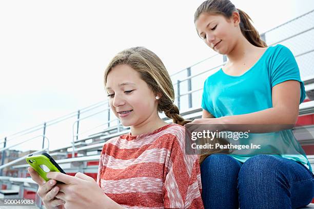 teenage girl braiding friend's hair in bleachers - girl who stands stock pictures, royalty-free photos & images