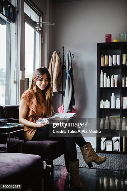 mixed race woman reading magazine in salon -  "suprijono suharjoto" or "take a pix media" stock pictures, royalty-free photos & images