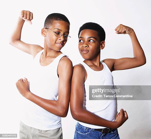 mixed race boys flexing their muscles - mixed race man standing studio stockfoto's en -beelden