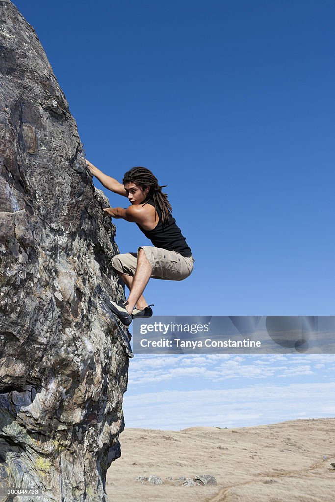 Hispanic climber scaling steep rock face