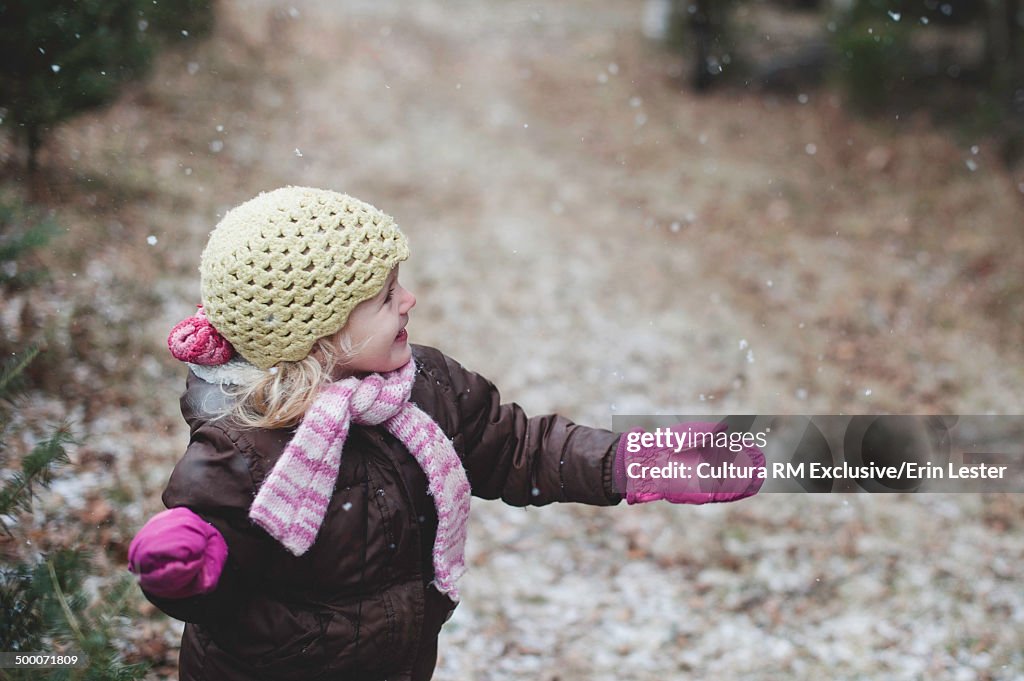 Girl wrapped up warm and excited by snow flurry