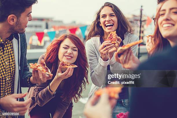 young people eating pizza at party - pizza stockfoto's en -beelden