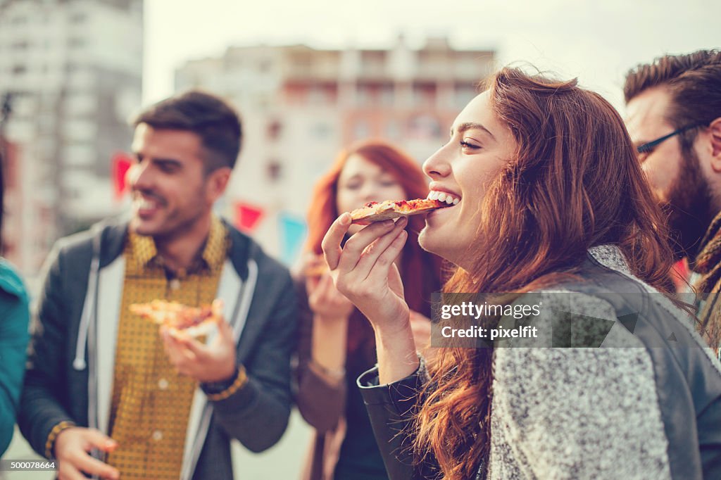Glückliche junge Menschen Essen pizza im Freien