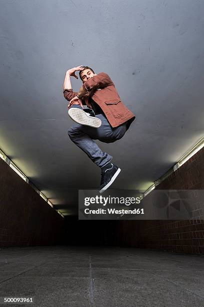 young breakdancer jumping in the air in underpass - nur junge männer stock-fotos und bilder