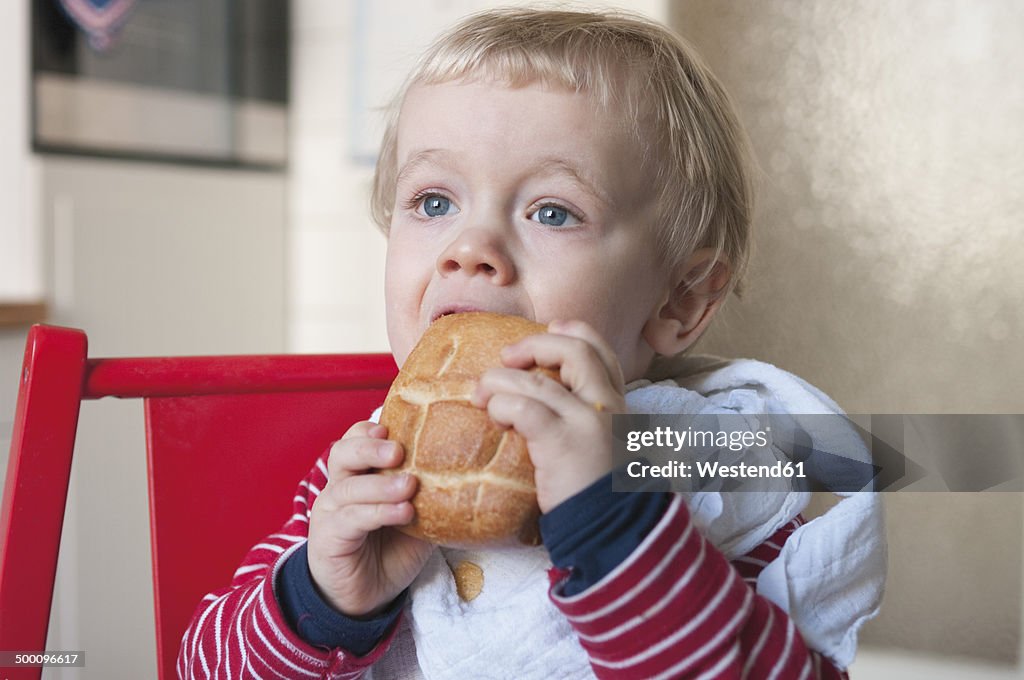 Germany, Baby boy eating bread roll