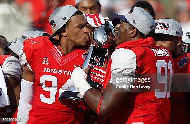 Cameron Malveaux of the Houston Cougars and Nick Thurman kiss the AAC championship trophy after defeating the Temple Owls 24-13 at TDECU Stadium on...