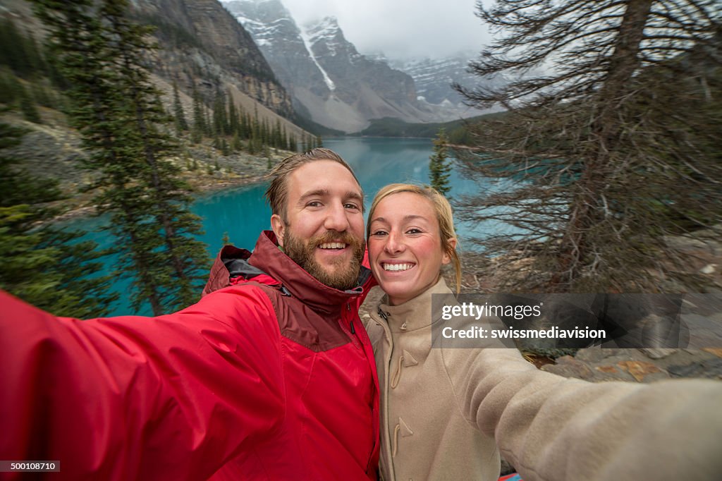 Cheerful young couple at Moraine lake taking a selfie portrait