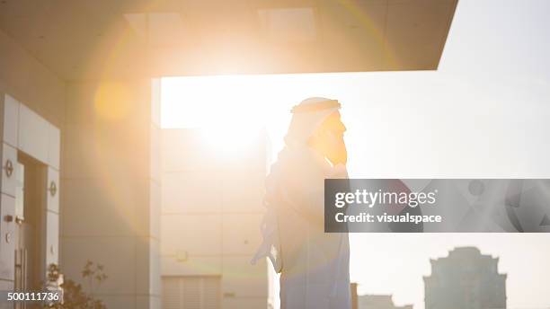 arab businessman talking on phone in evening sunlight - west asian ethnicity stock pictures, royalty-free photos & images