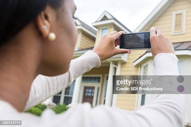 young woman taking photo of new home with smart phone - fotoberichten stockfoto's en -beelden