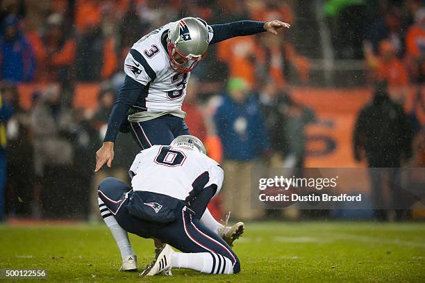 Kicker Stephen Gostkowski of the New England Patriots kicks a point after a touchdown as punter Ryan Allen place holds against the Denver Broncos at...