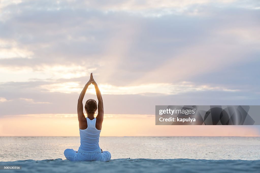 Caucasian woman practicing yoga at seashore