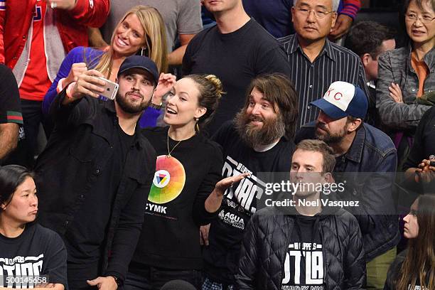 Olivia Wilde, Will Forte and Jason Sudeikis take a selfie with a fan at a basketball game between the Orlando Magic and Los Angeles Clippers at...