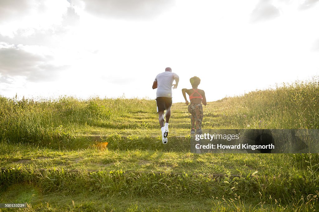 Couple running up grassy slope