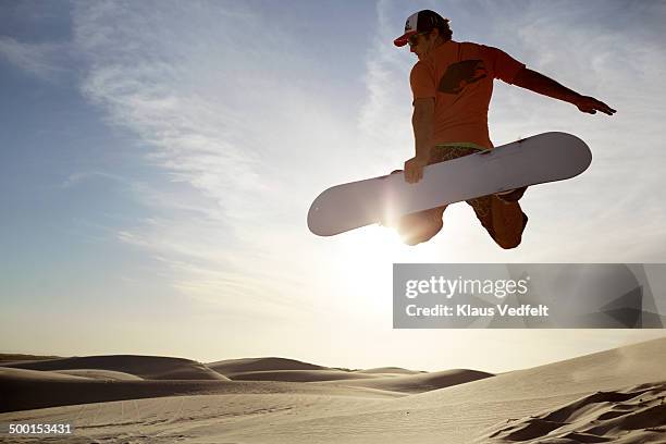 sandboarder doing "method" grab in the air - sand boarding stock pictures, royalty-free photos & images