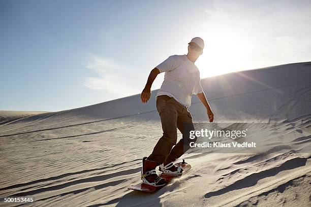 mature sandboarder cruising down dune - sand boarding stock pictures, royalty-free photos & images