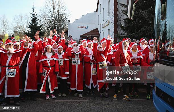 Participants dressed as Santa Claus wave their arms in a wave pattern to a passing bus as they wait to start in the 7th annual Michendorf Santa Run...