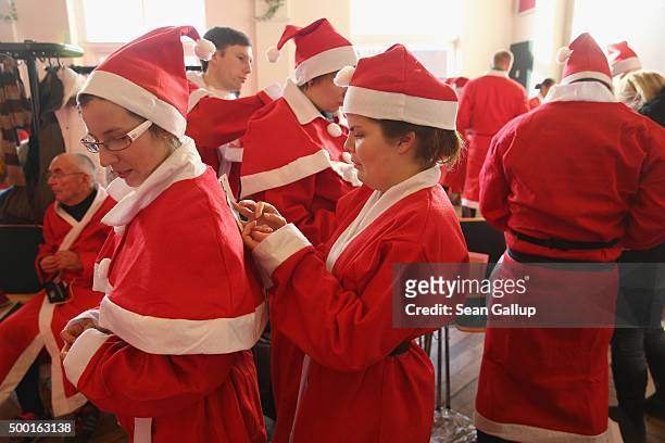 Participants dressed as Santa Claus dress into their costumes before taking part in the 7th annual Michendorf Santa Run on December 6, 2015 in...