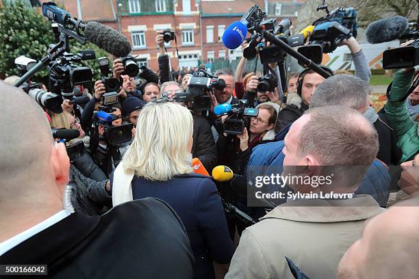 French Far-Right National Front President Marine Le Pen talks with journalists as she leaves the polling station after voting for the first round of...