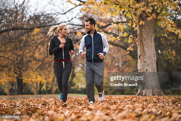 young happy couple jogging in autumn day and communicating. - s happy days stock pictures, royalty-free photos & images